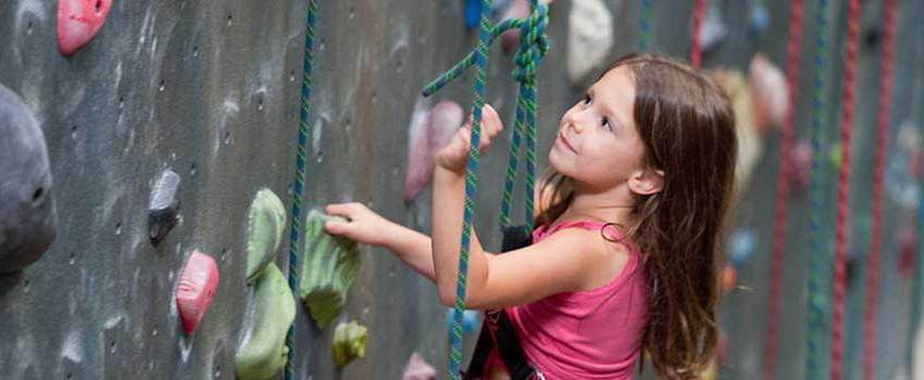 Young girl climbing rock wall.