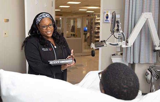 Nurse speaking with patient in hospital bed.