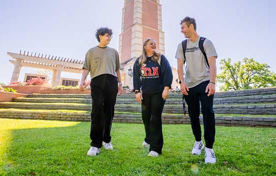 Three students smiling walking in front of Moulton Tower.